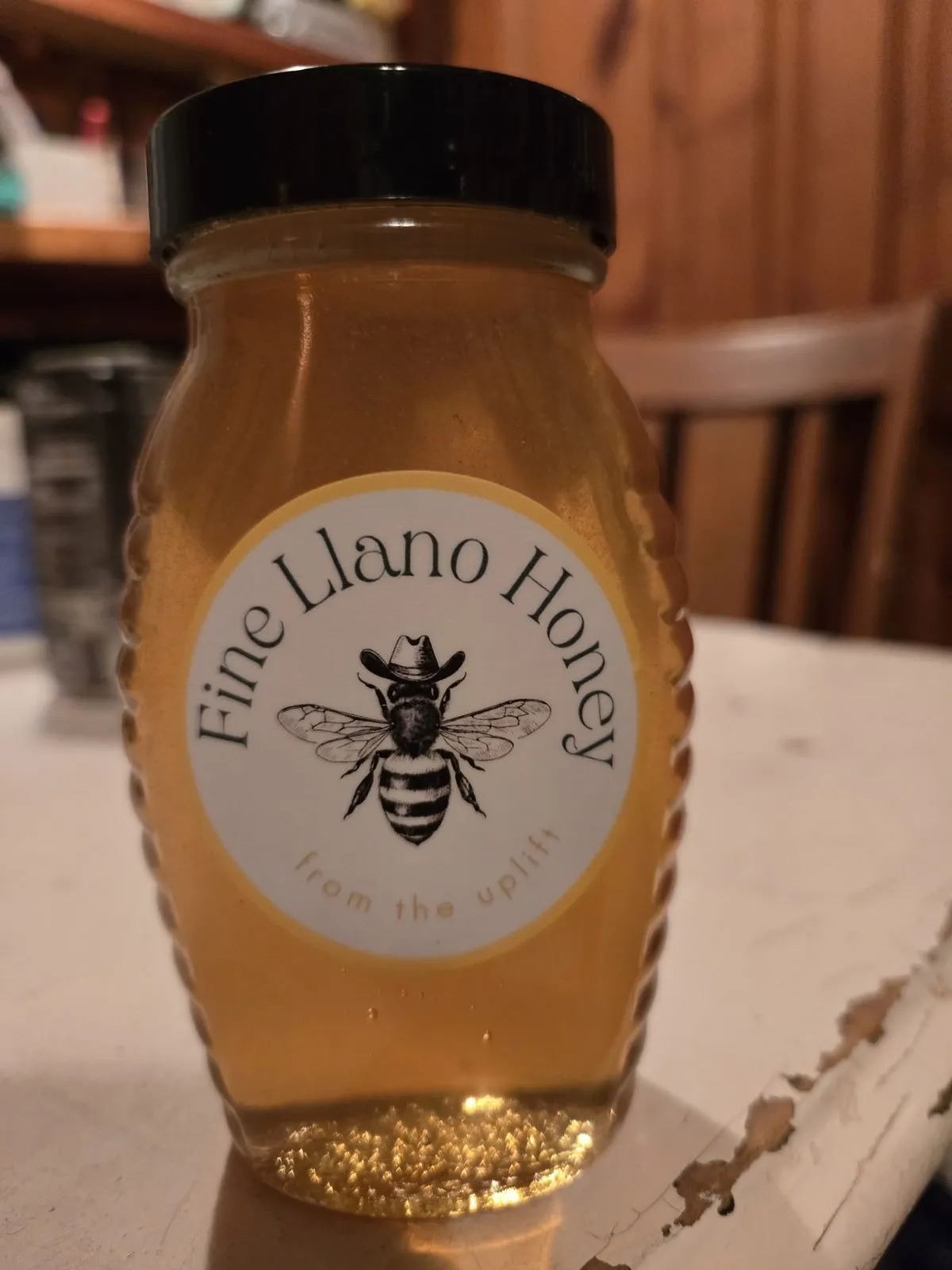 Upright jar of Fine Llano Honey, light amber, with a circular label of a bee in a cowboy hat